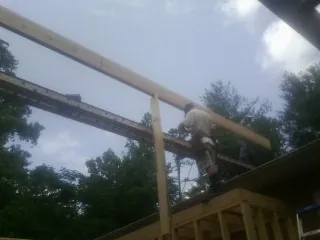Carpenter setting a ridge beam over a new addition frame — Ice Dam Removal by Roofing Brothers in Wellston
