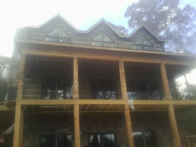 Dormers and porch framing on a large log home under construction — Roof Coating work by our crew in Wellston