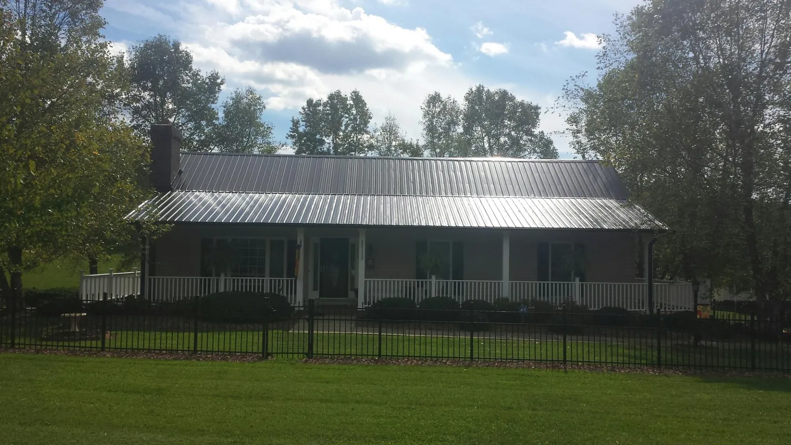 Gray metal roof on a brick ranch with a full width front porch — Gutter Guard Installation work by our crew in Wellston